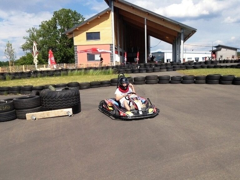 Eine Person fährt ein Go-Kart auf einer Rennstrecke und genießt den Aktivurlaub.
