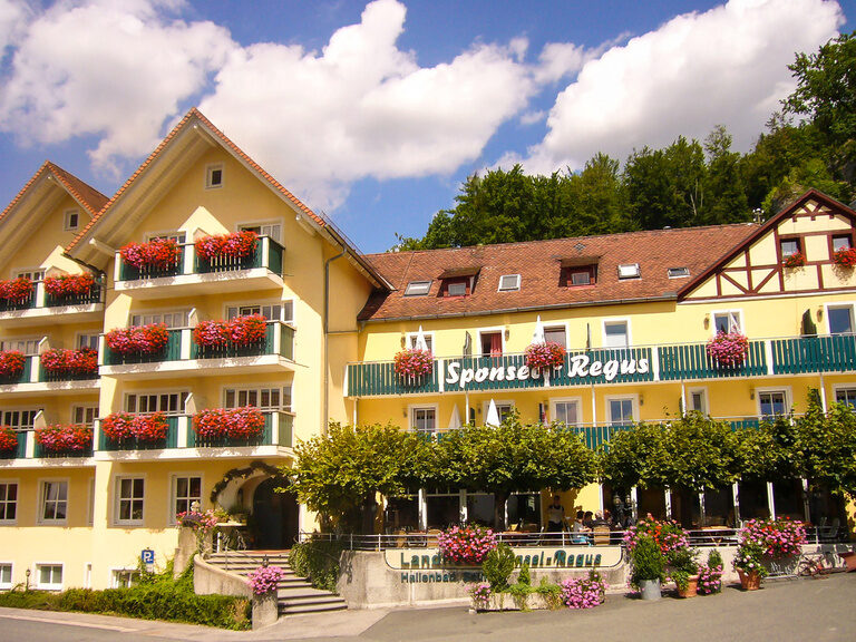 Das gelbe Hotelgebäude von Sponsel-Regus an einem schönen Sommertag mit strahlend blauen Himmel