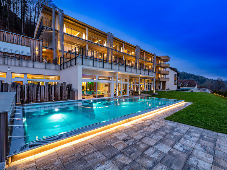 Außenansicht des Wellnesshotels Sponsel-Regus in Franken mit Außenpool und Hotelgebäude in der Abenddämmerung.