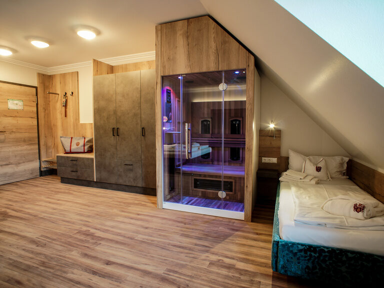 Ein gemütliches Schlafzimmer mit einem Bett und einem Fernseher im Familienzimmer Mattstein