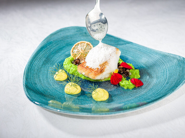 Ein blauer Teller präsentiert ein kunstvoll angerichtetes Dessert im Restaurant Sponsel-Regus