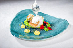 Ein blauer Teller präsentiert ein kunstvoll angerichtetes Dessert im Restaurant Sponsel-Regus