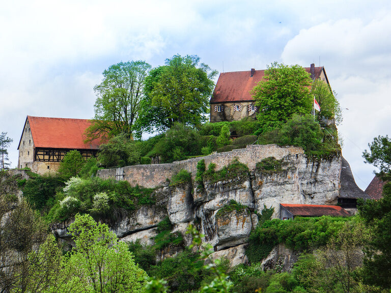Eine majestätische Burg auf einem Hügel umgeben von Bäumen in Gößweinstein, Franken.