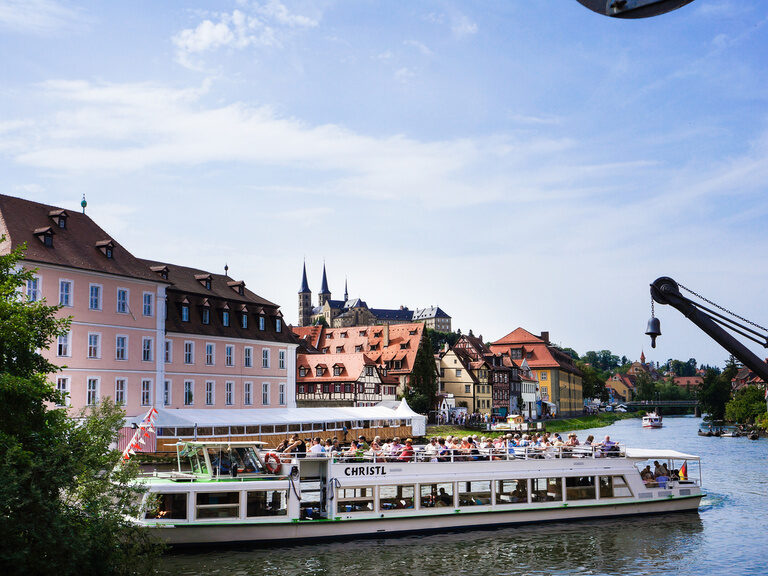 Ein Schiff mit Besuchern vor der Altstadt von Bamberg.