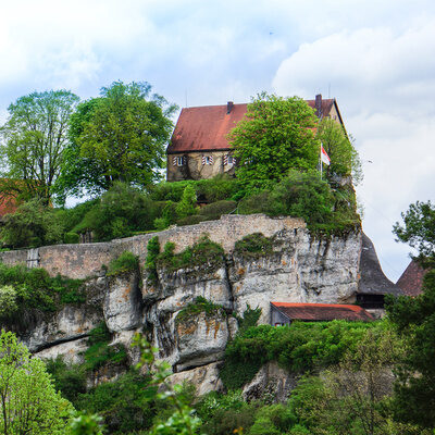 Eine majestätische Burg auf einem Hügel umgeben von Bäumen in Gößweinstein, Franken.