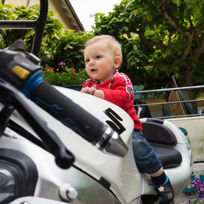 Ein Baby sitzt lächelnd auf dem Rücksitz eines Motorrads in der Nähe des Hotels Sponsel-Regus
