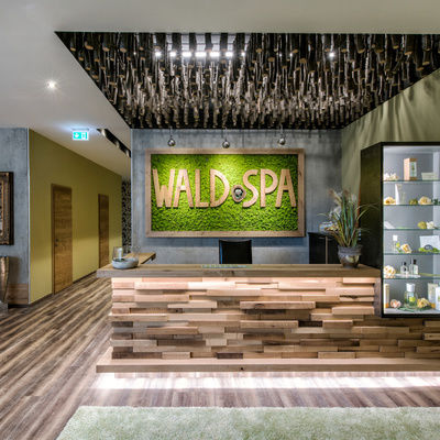 Der einladende Eingangsbereich des Wald Spa mit naturfarbenem Holzboden und beruhigenden grünen Wänden
