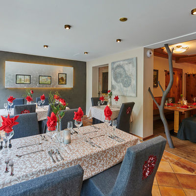 Ein stilvoller Restaurant-Innenraum mit eleganten blauen Stühlen um die schön gedeckten Tische im Hotel Sponsel-Regus