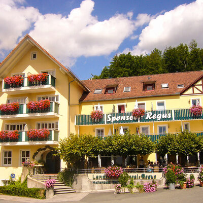 Das gelbe Hotelgebäude von Sponsel-Regus an einem schönen Sommertag mit strahlend blauen Himmel