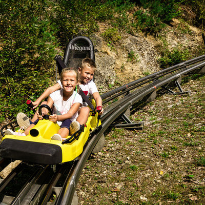 Zwei Kinder fahren mit der Rodelbahn der Erlebnismeile Pottenstein und haben Spaß