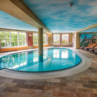 Ein luxuriöser Innenpool mit einem gemalten Himmelsmotiv an der Decke.