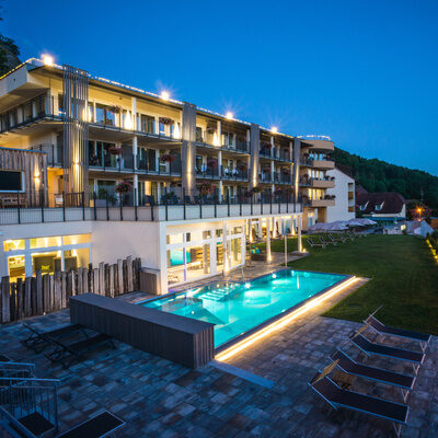 Panorama-Ansicht des Wellnesshotel Sponsel-Regus Schlössla mit beleuchtetem Pool