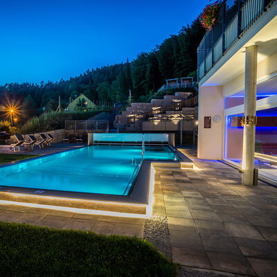 Ein beleuchteter Swimmingpool im Wellnessbereich bei Nacht im Landhaus Sponsel-Regus in Franken