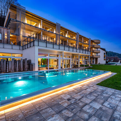 Außenansicht des Wellnesshotels Sponsel-Regus in Franken mit Außenpool und Hotelgebäude in der Abenddämmerung.