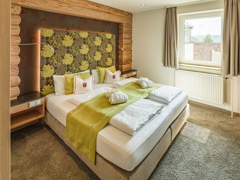 Ein komfortables Bett mit einem hölzernen Bettrahmen in der einladenden Natur-Suite Schwalbennest