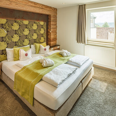 Ein komfortables Bett mit einem hölzernen Bettrahmen in der einladenden Natur-Suite Schwalbennest