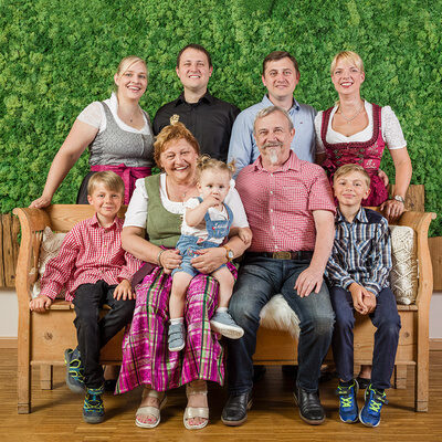 Die Gastgeberfamilie Regus sitzt auf einer Bank vor einer grünen Wand im Landhaus Sponsel-Regus