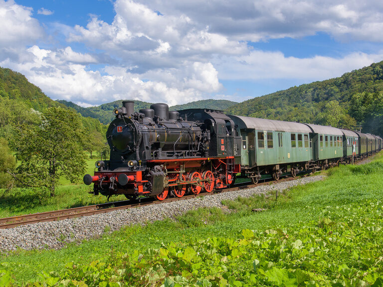 Die Dampfbahn Fränkische Schweiz fährt an einem sonnigen Tag die Gleise entlang.