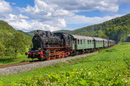 Die Dampfbahn Fränkische Schweiz fährt an einem sonnigen Tag die Gleise entlang.