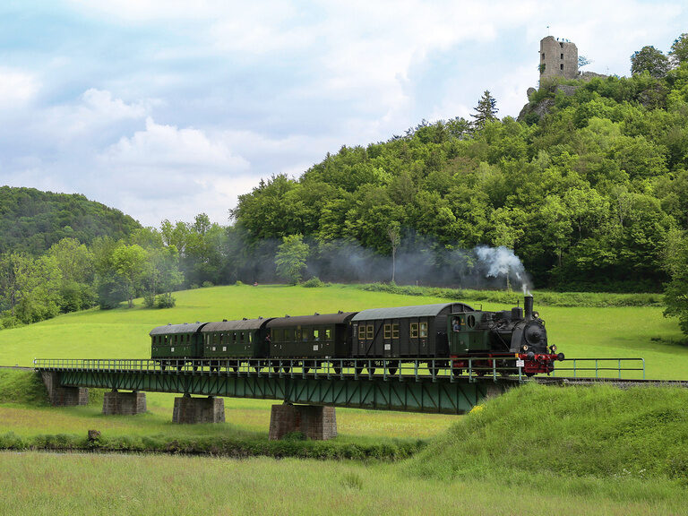 Ein Zug der Dampfbahn Fränkische Schweiz fährt über eine Brücke.