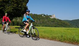 Radfahrer auf E-Bikes mit Burgruine Neideck im Hintergrund