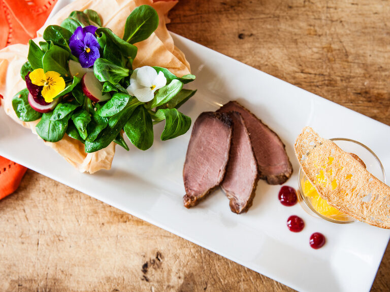 Ein weißer Teller ist mit Fleisch und Gemüse angerichtet.