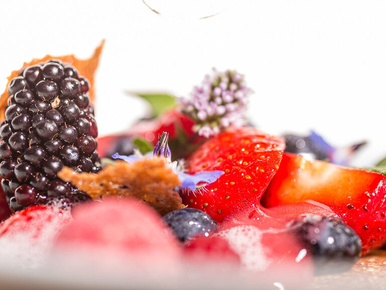 Ein weißer Teller ist mit Früchten und Beeren belegt.