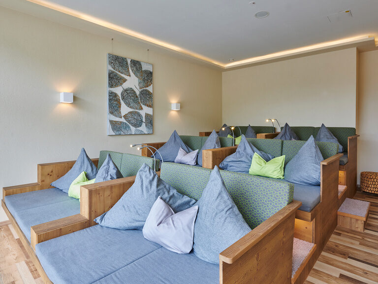 Ein heller Ruhebereich im Wald-Spa mit Couch und Laminatboden für entspannten Komfort.