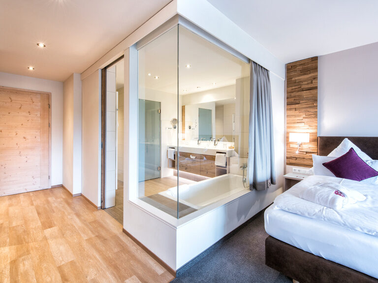 Das moderne Badezimmer in der Juniorsuite Schloessla hat eine Glaswand direkt zum Schlafbereich