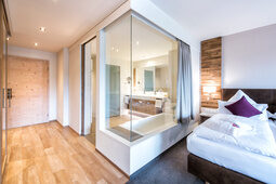 Das moderne Badezimmer in der Juniorsuite Schloessla hat eine Glaswand direkt zum Schlafbereich