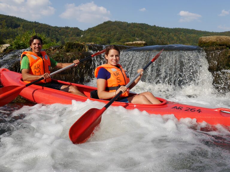 Zwei Kanuten nahe einem Wasserfall in der Wiesent beim Kanu fahren