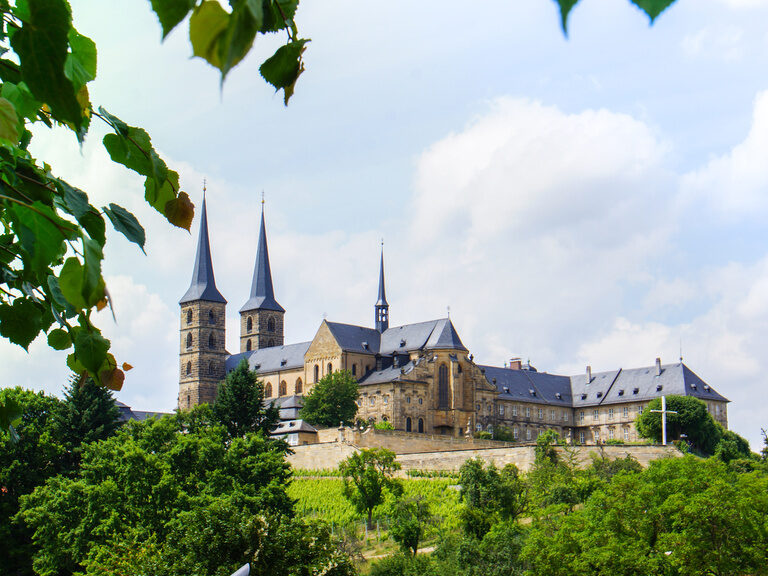 Blick auf das Kloster Michaelsberg mit grüner Landschaft im Vordergrund