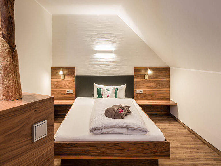 Ein bequemes Bett sowie edles Holzmobilar in der Komfort-Suite Mattstein