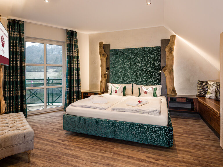 Ein großes Bett mit einem eleganten Holzrahmen in der geräumigen Komfort-Suite Mattstein