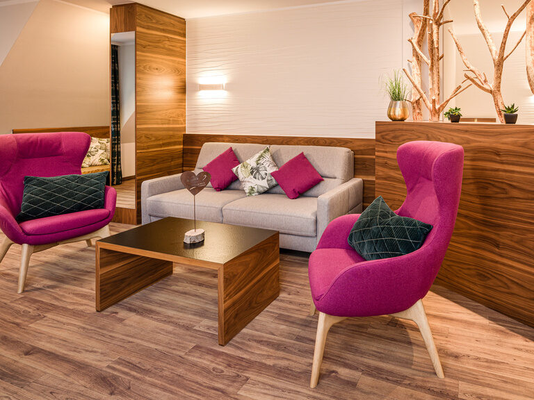 Das elegante Wohnzimmer mit zwei bequemen pinken Sesseln in der Komfort-Suite Mattstein