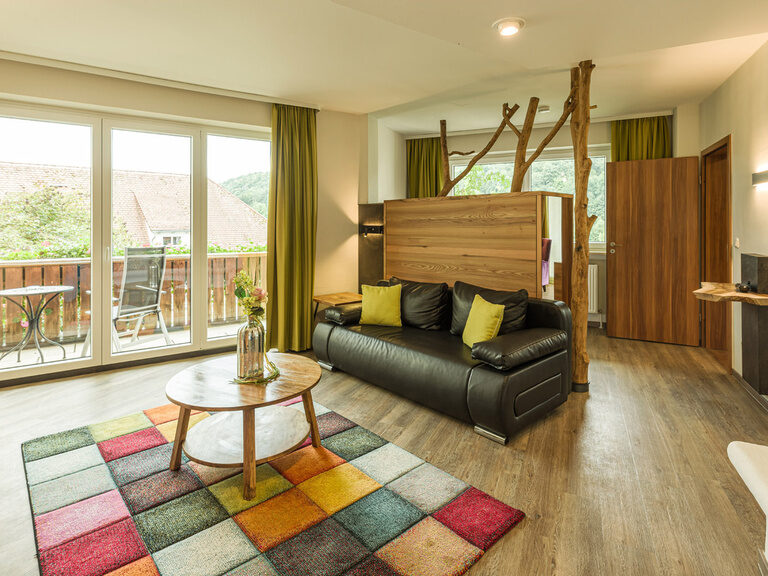 Im hellen Wohnbereich der Landhaus Suite Sonneck lädt eine bequeme Couch zum Entspannen ein.