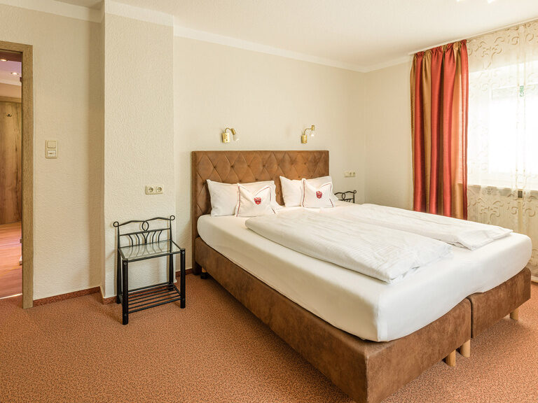 Das elegant eingerichtete Familienzimmer im Gästehaus mit einem Bett und viel natürlichem Licht.