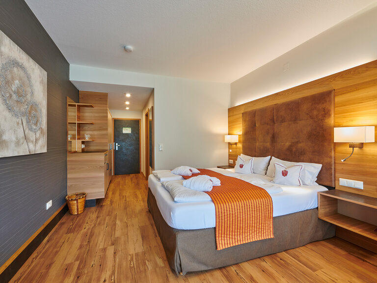 Das stilvolle Schlafzimmer im Komfortdoppelzimmer im Haus Sonneck, das mit Holzelementen ausgestattet ist.