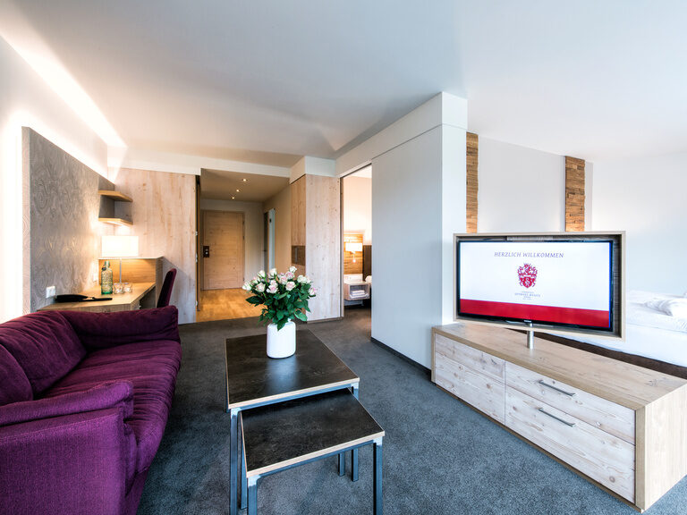Ein einladendes Wohnzimmer mit gemütlicher Couch und einem modernen Flachbildfernseher - Landhaus Sponsel-Regus.