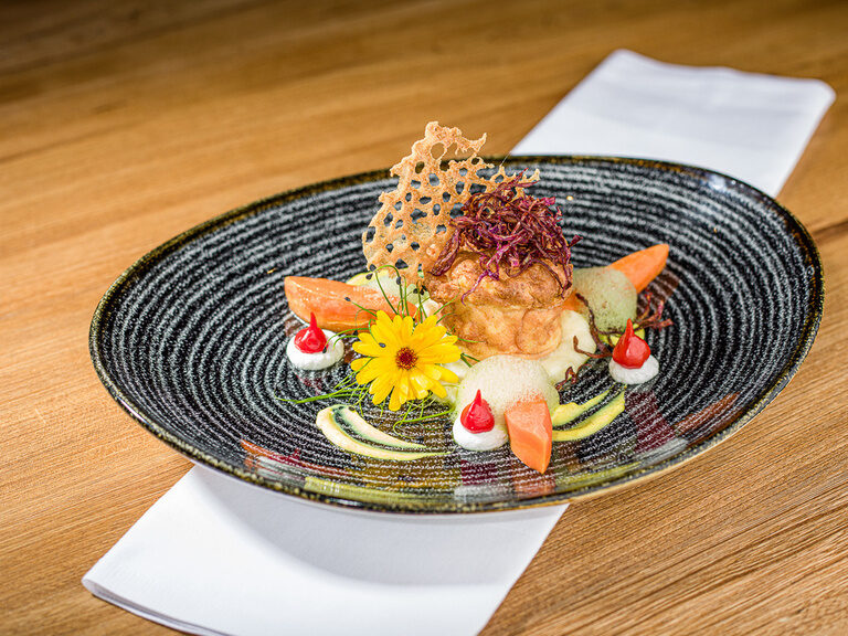 Ein Teller mit Speisen und Gerichten liegt auf einem Holztisch.