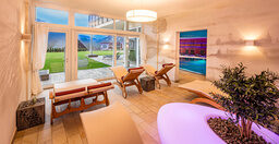 Ein geschmackvoll eingerichteter Ruhebereich im Wellnesshotel mit großem Fenster und stilvollen Möbeln.