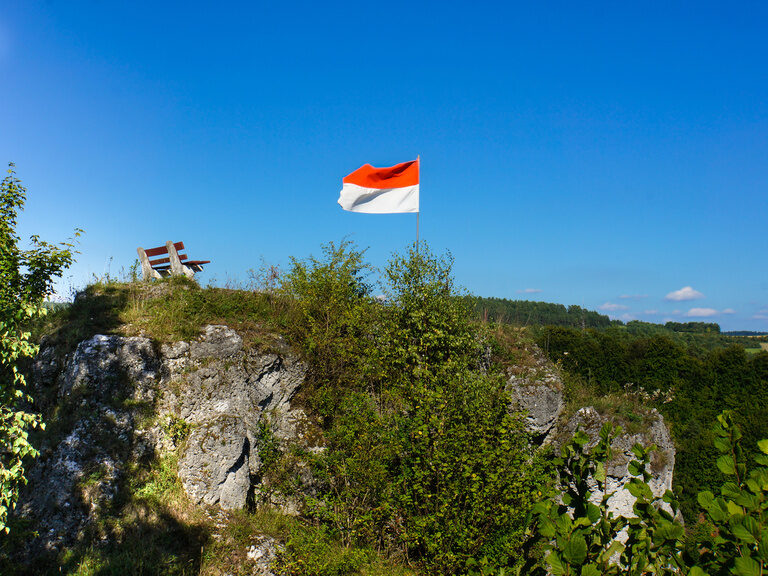 Eine Flagge weht im Wind über einer felsigen Klippe.
