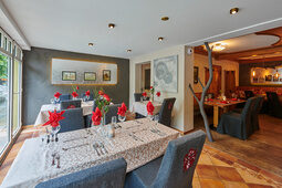 Ein stilvoller Restaurant-Innenraum mit eleganten blauen Stühlen um die schön gedeckten Tische im Hotel Sponsel-Regus