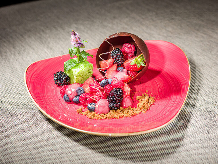 Ein roter Teller ist mit Früchten und Schokolade belegt.