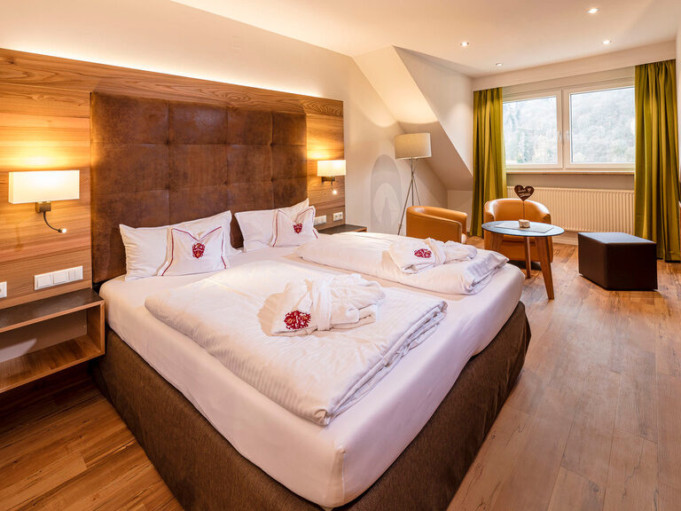 Das geräumige Komfort-Doppelzimmer Sonneck ohne Balkon mit einem großen Bett und hölzernen Wänden.