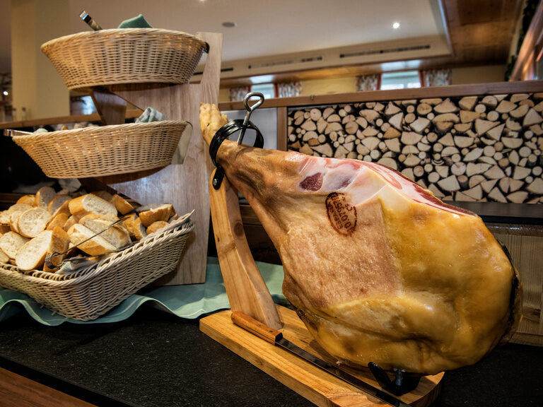 Ein großes Stück edler Schinken auf einem hölzernen Schneidebrett im Restaurant des Landhaus Sponsel-Regus.