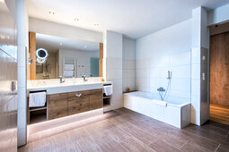 Ein luxuriöses Badezimmer in der Turm-Familiensuite des Hotels Sponsel-Regus mit Badewanne, Waschbecken und Spiegel.