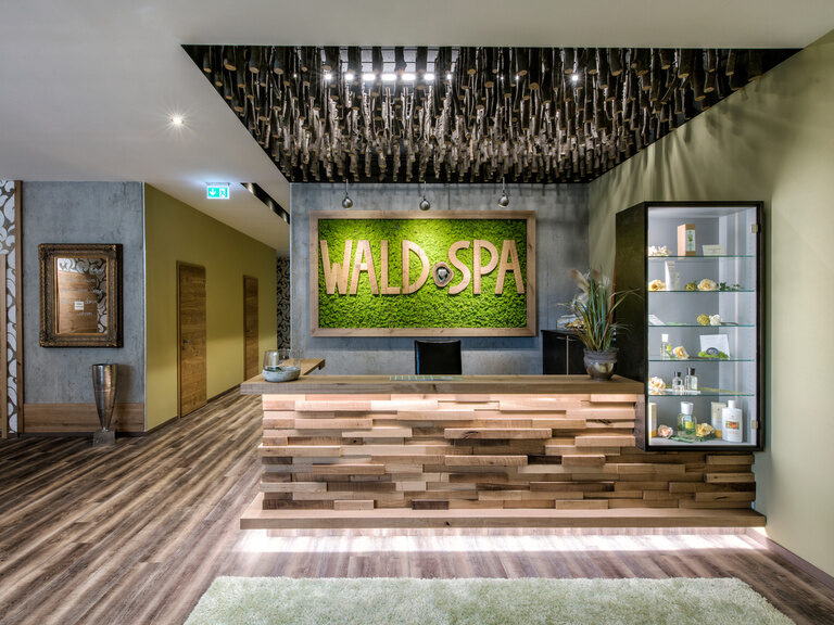 Der einladende Eingangsbereich des Wald Spa mit naturfarbenem Holzboden und beruhigenden grünen Wänden