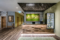 Der einladende Eingangsbereich des Wald Spa mit naturfarbenem Holzboden und beruhigenden grünen Wänden