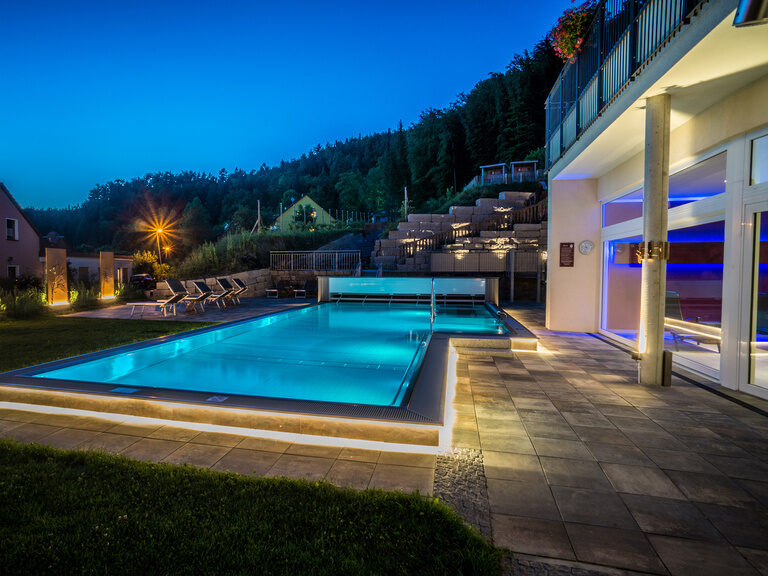 Ein beleuchteter Swimmingpool im Wellnessbereich bei Nacht im Landhaus Sponsel-Regus in Franken